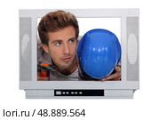 Young man and his hard hat stuck in a television screen. Стоковое фото, агентство Ingram Publishing / Фотобанк Лори