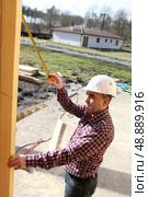 Man measuring wood beam. Стоковое фото, агентство Ingram Publishing / Фотобанк Лори