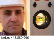 Builder knelt holding spirit level. Стоковое фото, агентство Ingram Publishing / Фотобанк Лори