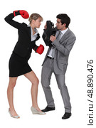 businesswoman threatening male colleague with boxing gloves. Стоковое фото, агентство Ingram Publishing / Фотобанк Лори