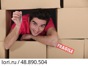 portrait of young man amid removal boxes holding key. Стоковое фото, агентство Ingram Publishing / Фотобанк Лори