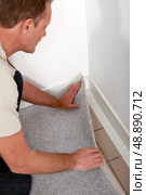 Man laying carpet into the corner of a room. Стоковое фото, агентство Ingram Publishing / Фотобанк Лори