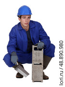 Worker holding a cinder block and trowel. Стоковое фото, агентство Ingram Publishing / Фотобанк Лори