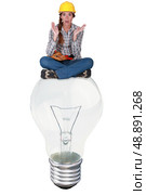 Woman with expression of surprise sat on a big light bulb. Стоковое фото, агентство Ingram Publishing / Фотобанк Лори