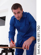 carpenter using a steel measuring tape for drawing a mark on a board. Стоковое фото, агентство Ingram Publishing / Фотобанк Лори
