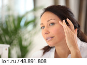 a woman spreading out cosmetic cream on her face. Стоковое фото, агентство Ingram Publishing / Фотобанк Лори