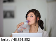 portrait of classy brunette working on laptop with bottle of water. Стоковое фото, агентство Ingram Publishing / Фотобанк Лори