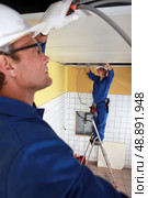 Laborers installing piping in ceiling. Стоковое фото, агентство Ingram Publishing / Фотобанк Лори