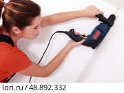 handywoman drilling a hole in the ceiling. Стоковое фото, агентство Ingram Publishing / Фотобанк Лори