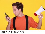 Confused man with a loudspeaker and walky-talky. Стоковое фото, агентство Ingram Publishing / Фотобанк Лори