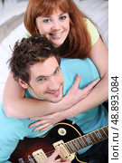 Young couple at home with a guitar. Стоковое фото, агентство Ingram Publishing / Фотобанк Лори