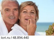 mature woman in bathrobe at spa resort eating grapes with husband. Стоковое фото, агентство Ingram Publishing / Фотобанк Лори