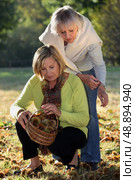 Mother and daughter gathering chestnuts in garden. Стоковое фото, агентство Ingram Publishing / Фотобанк Лори