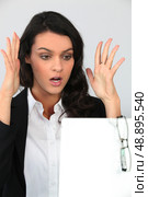 Woman holding her hands up in shock at a board left blank for your message. Стоковое фото, агентство Ingram Publishing / Фотобанк Лори