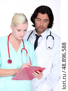 a doctor and a nurse looking seriously a paper. Стоковое фото, агентство Ingram Publishing / Фотобанк Лори