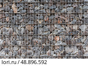 Close-up view of a metal wire fence frame filled with rocks. Gabion. Стоковое фото, фотограф EugeneSergeev / Фотобанк Лори