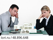 Two uninspired architects sat by model housing. Стоковое фото, агентство Ingram Publishing / Фотобанк Лори