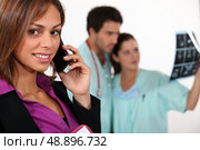 Businesswoman on phone and carers observing an x-ray. Стоковое фото, агентство Ingram Publishing / Фотобанк Лори