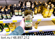 Оливковое масло Extra Virgin Filippo Berio в руке в супермаркете. Различные бутилированные оливковые масла. Редакционное фото, фотограф FotograFF / Фотобанк Лори