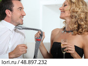 Woman drinking champagne whilst grabbing mans tie. Стоковое фото, агентство Ingram Publishing / Фотобанк Лори