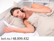 Young woman using her cellphone in bed. Стоковое фото, агентство Ingram Publishing / Фотобанк Лори
