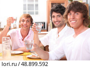 Three young men eating a meal together and drinking water. Стоковое фото, агентство Ingram Publishing / Фотобанк Лори