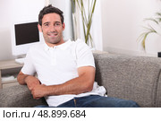 35 years old man sitting in a comfortable couch. Стоковое фото, агентство Ingram Publishing / Фотобанк Лори