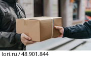 A person is passing a box to another person in a simple exchange of goods or items. Стоковое AI-изображение, AI-художник Данила Большаков / Фотобанк Лори