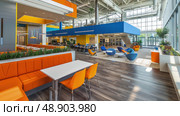 A spacious room packed with numerous chairs and tables, creating a setting suitable for gatherings, meetings, or conferences. Стоковое AI-изображение, AI-художник Данила Большаков / Фотобанк Лори