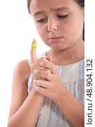 little girl watching a bandage on her finger. Стоковое фото, агентство Ingram Publishing / Фотобанк Лори