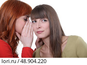 Woman whispering into her friend’s ear. Стоковое фото, агентство Ingram Publishing / Фотобанк Лори