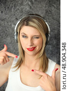 Woman winking with audio headphones. Стоковое фото, агентство Ingram Publishing / Фотобанк Лори
