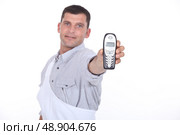 Dark haired man holding out mobile telephone. Стоковое фото, агентство Ingram Publishing / Фотобанк Лори