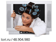 Woman wearing hair rollers escaping from television. Стоковое фото, агентство Ingram Publishing / Фотобанк Лори