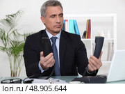 Over worked businessman holding two telephones. Стоковое фото, агентство Ingram Publishing / Фотобанк Лори