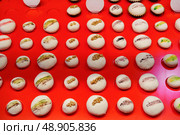 Colorful macarons arranged neatly on a bright red display reflecting an artful pastry shop environment. Стоковое фото, фотограф Сергей Толмачёв / Фотобанк Лори
