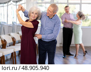 Smiling elderly woman and partner successfully perform mesmerizing movements of paso doble dance. Стоковое фото, фотограф Яков Филимонов / Фотобанк Лори
