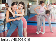 Emotional woman trying to escape from back grip and delivering elbow strike to midsection to female opponent during mock bout in self defense training. Стоковое фото, фотограф Яков Филимонов / Фотобанк Лори
