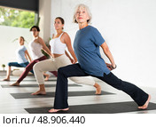 Woman with group of adult people doing stretching workout for body flexibility in yoga studio. Стоковое фото, фотограф Яков Филимонов / Фотобанк Лори