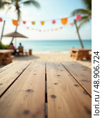 Warm sunlight bathes the wooden table in front of a serene beach, where colorful decorations sway gently in the breeze and the ocean sparkles invitingly beyond Generative AI. Стоковое AI-изображение, AI-художник Юлия Петровская / Фотобанк Лори
