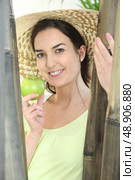 Woman wearing hat and holding green apple. Стоковое фото, агентство Ingram Publishing / Фотобанк Лори