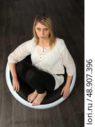 Woman sat barefoot in designer chair. Стоковое фото, агентство Ingram Publishing / Фотобанк Лори