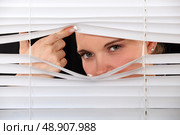 Curious woman peering through window blinds. Стоковое фото, агентство Ingram Publishing / Фотобанк Лори