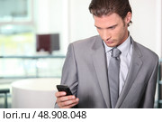 Male executive checking messages on cellphone. Стоковое фото, агентство Ingram Publishing / Фотобанк Лори