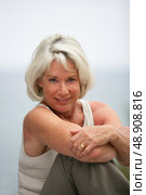 Happy gray-haired lady sat by the coast. Стоковое фото, агентство Ingram Publishing / Фотобанк Лори