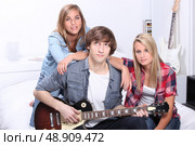 Teenager with guitar sat with friends. Стоковое фото, агентство Ingram Publishing / Фотобанк Лори