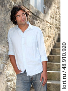 Man abroad leaning against old stone wall. Стоковое фото, агентство Ingram Publishing / Фотобанк Лори