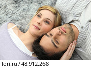 Couple lying on carpet. Стоковое фото, агентство Ingram Publishing / Фотобанк Лори