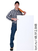 Roofer with tile pointing at blank poster. Стоковое фото, агентство Ingram Publishing / Фотобанк Лори