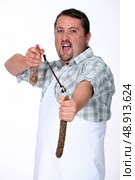 Angry butcher fighting with sausages. Стоковое фото, агентство Ingram Publishing / Фотобанк Лори
